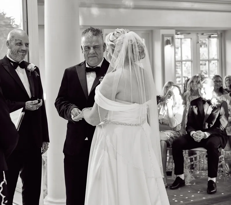 Black and white photo of the bride arriving at the ceremony at Friern Manor