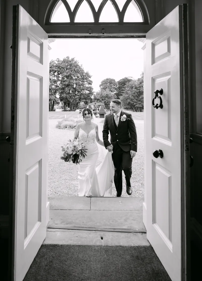 Black and white photo of the couple framed in the front doorway at Chilston Park