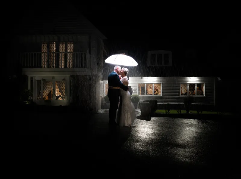Couple under a clear umbrella at night outside Rowhill Grange