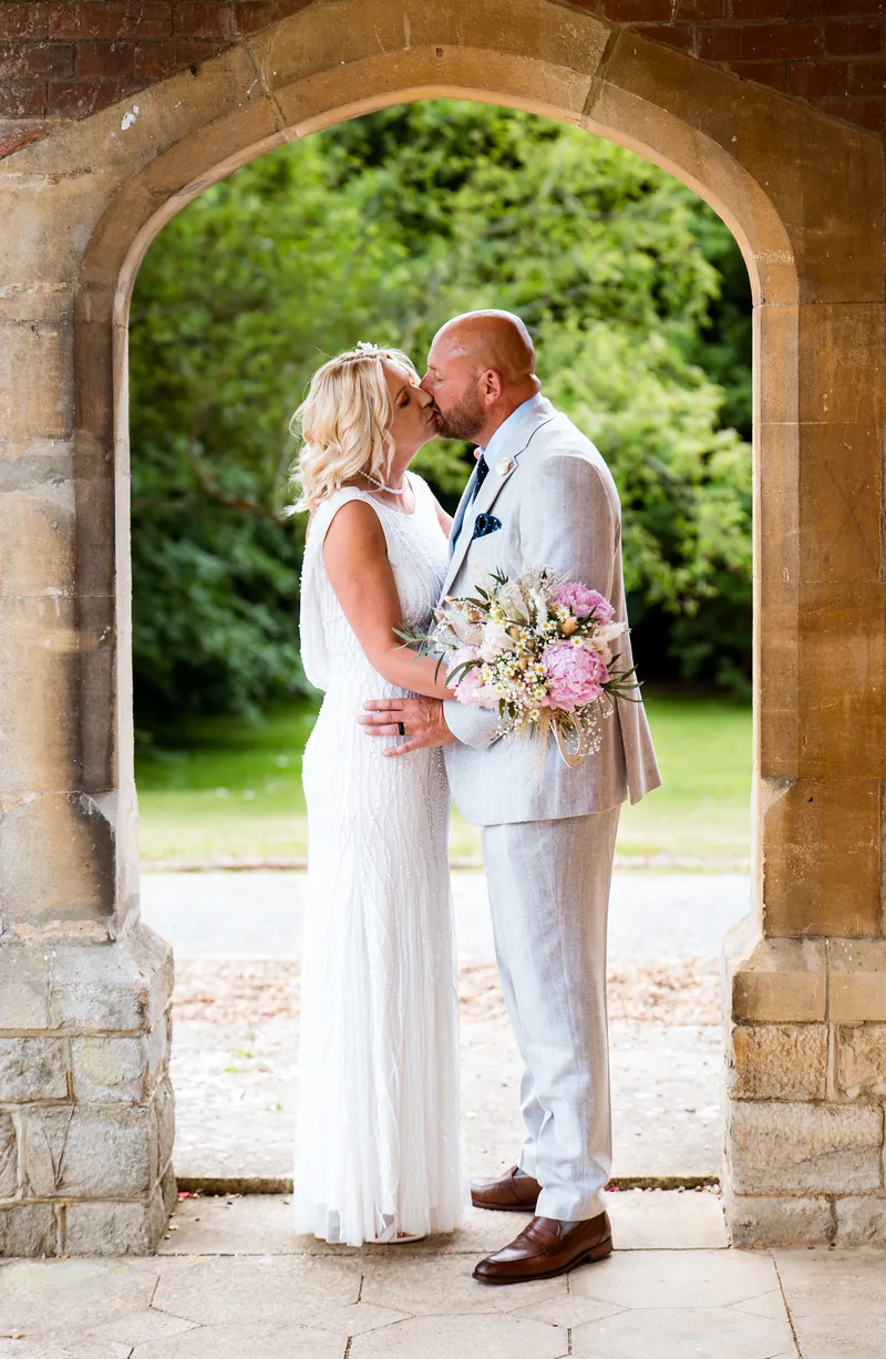 Couple kissing in the brick arch at Oakwood House, Maidstone