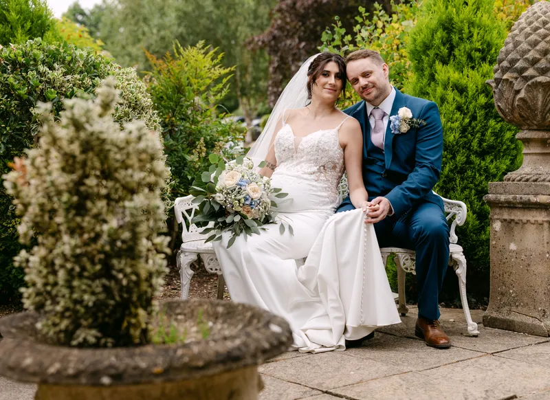 Bride and groom on a garden bench at Chilston Park Hotel