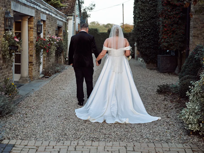 Bride and groom walking along a garden path at Friern Manor