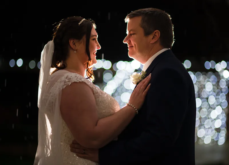 Couple facing each other at dusk with lights behind