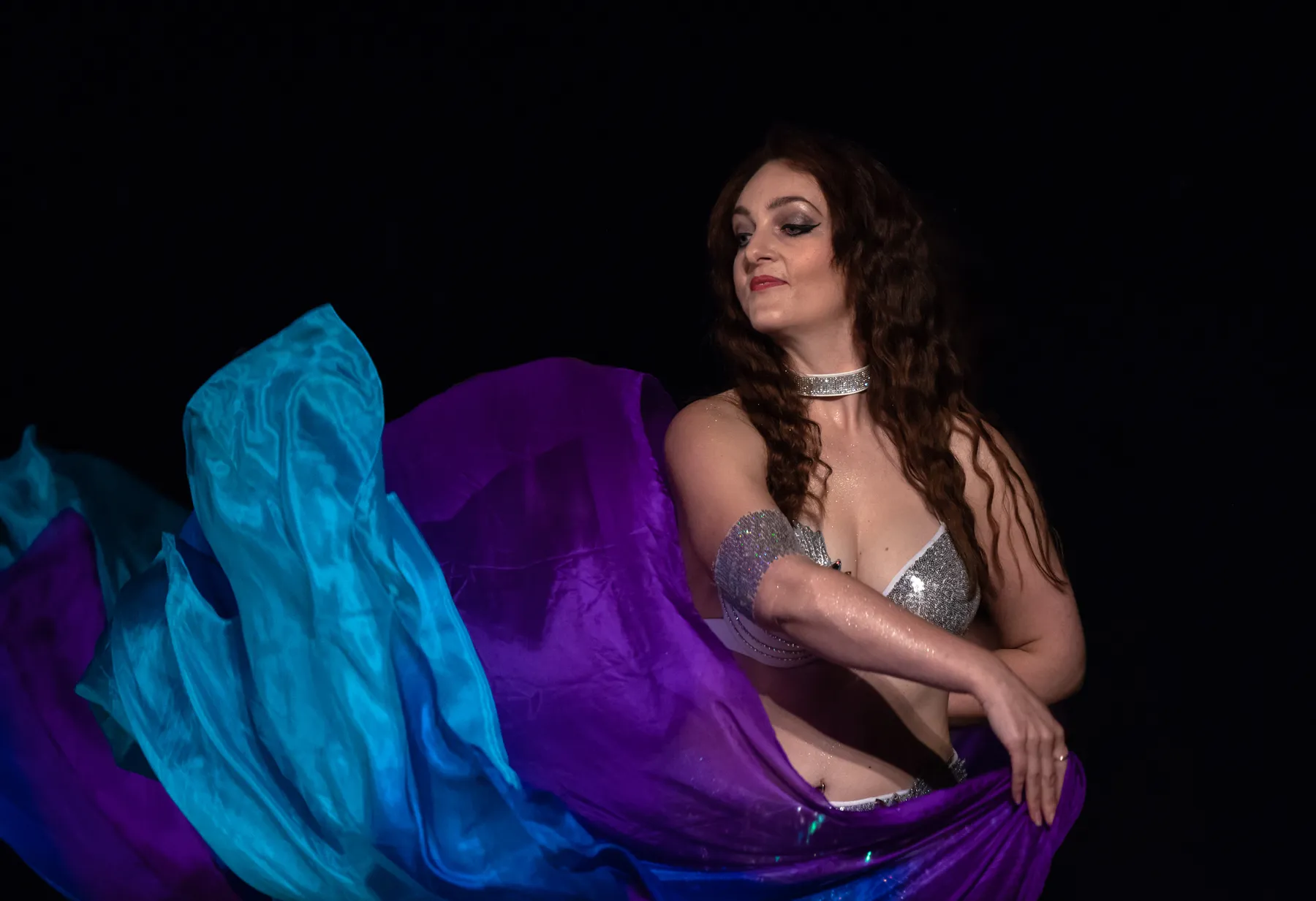 Dancer performing with flowing purple and blue silk veils on stage