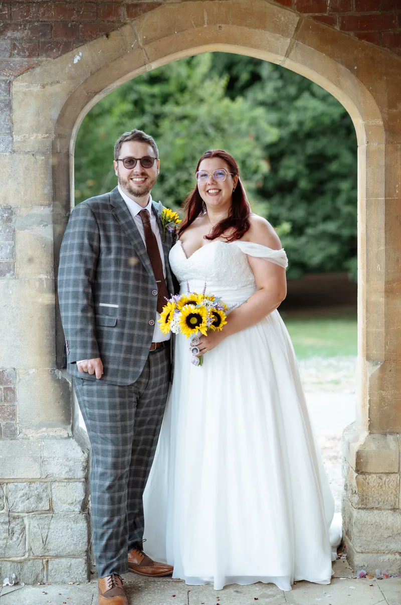 Couple with sunflower bouquet in the brick arch at Oakwood House