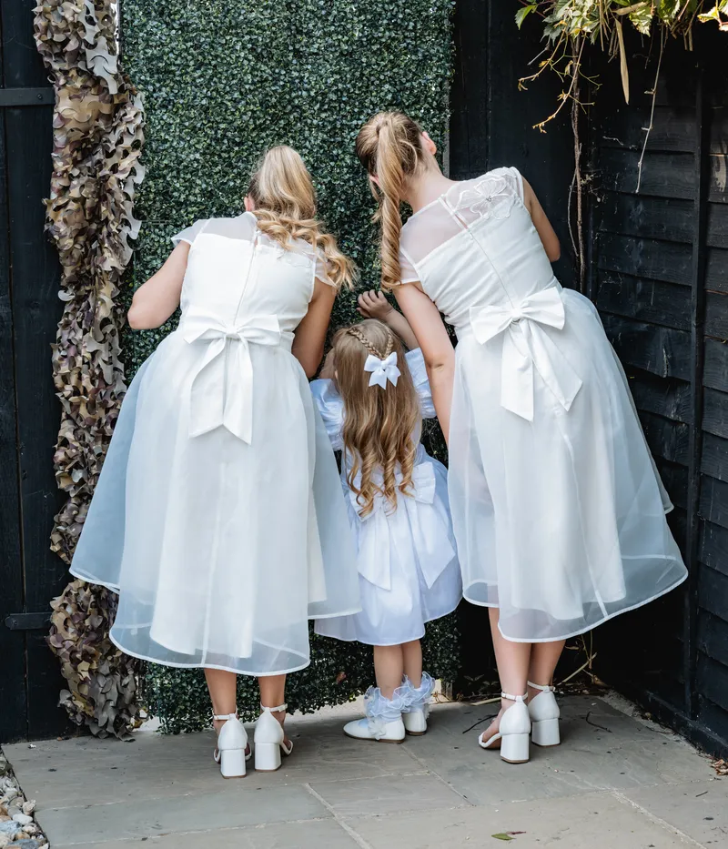 Bridesmaids and flower girl peeking round a corner at The Orchard