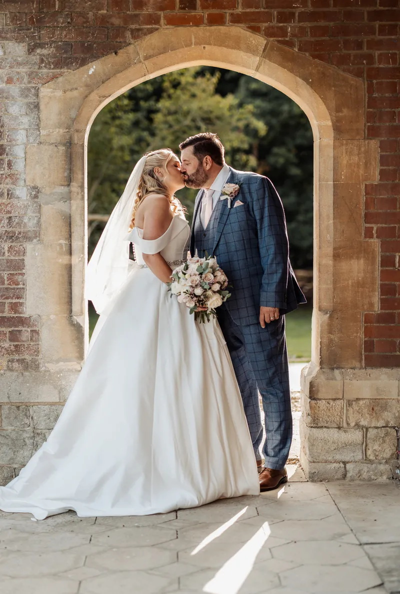 Couple kissing under the brick arch outside the Garden Room at Oakwood House