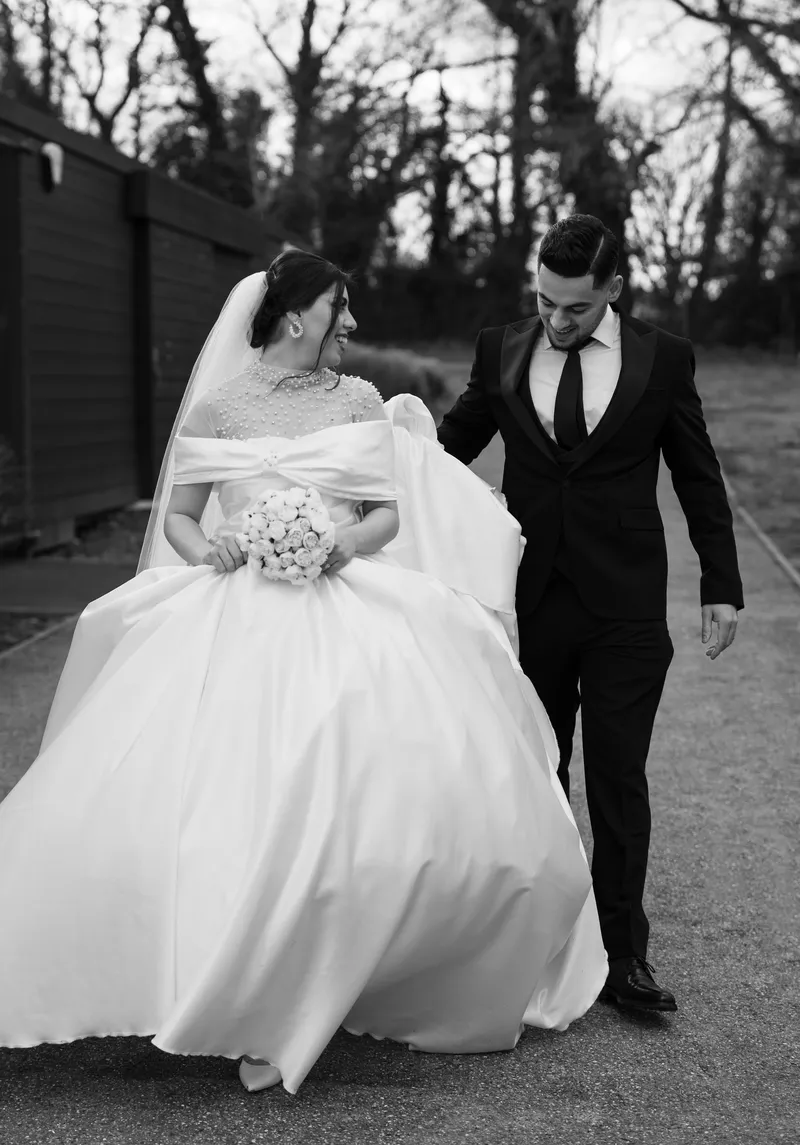 Black and white photo of the couple walking, her dress flowing
