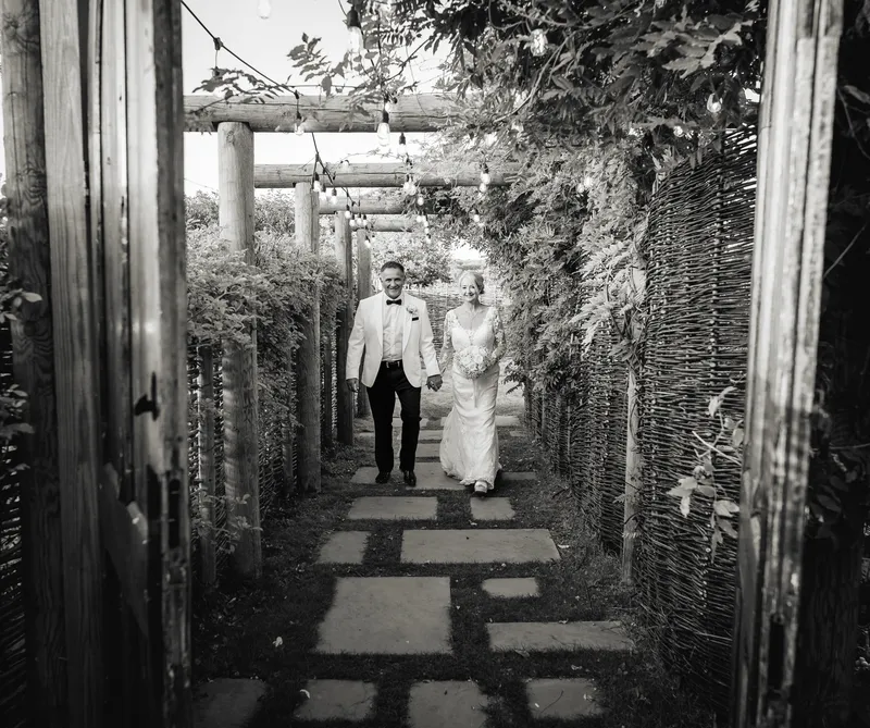 Black and white photo of the couple on a garden path at The Orchard