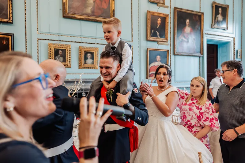 Groom carrying the page boy on his shoulders in a conga through the portrait room at Bradbourne House
