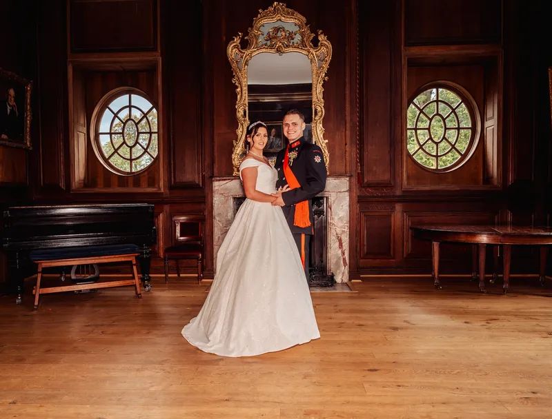 Couple in front of the gilded mirror and marble fireplace at Bradbourne House