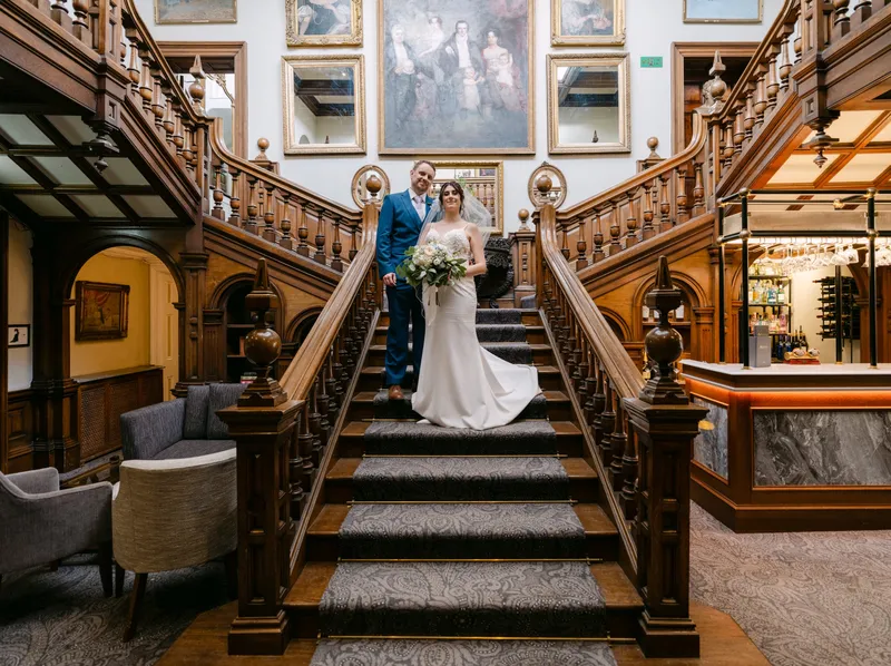 Bride and groom on the grand carved staircase at Chilston Park Hotel, Lenham