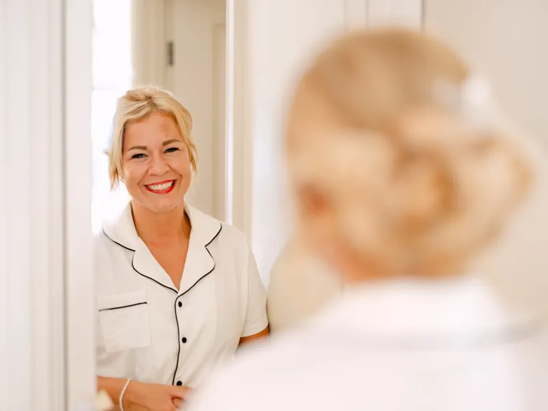 Bride smiling at her reflection on the wedding morning