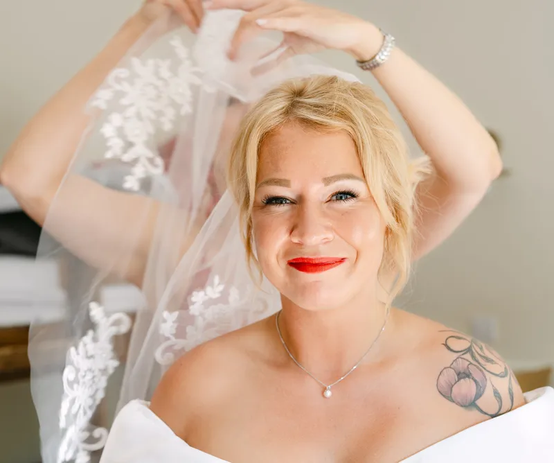 Bride smiling as her veil is put in place on the wedding morning