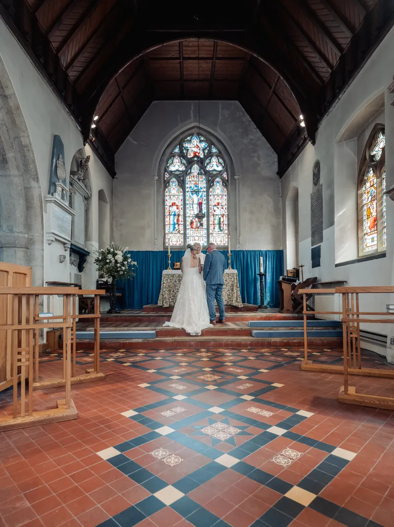 Wedding ceremony at the altar beneath a stained glass window in a Kent church
