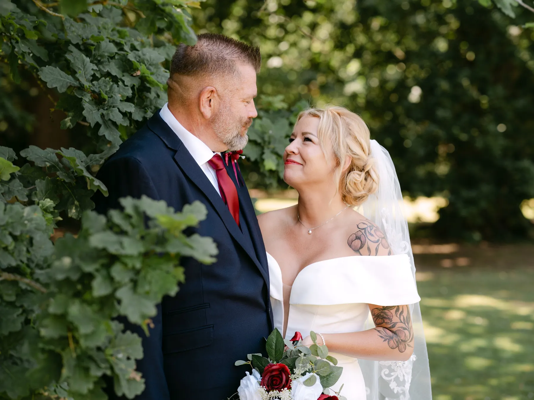 Bride smiling up at the groom under oak leaves at a summer wedding in Kent