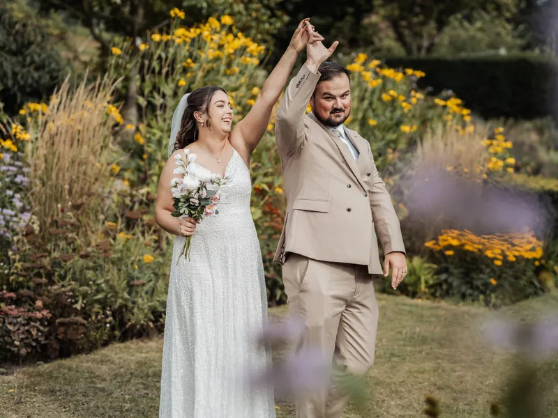 Bride and groom twirling in front of a summer flower border at a Kent wedding