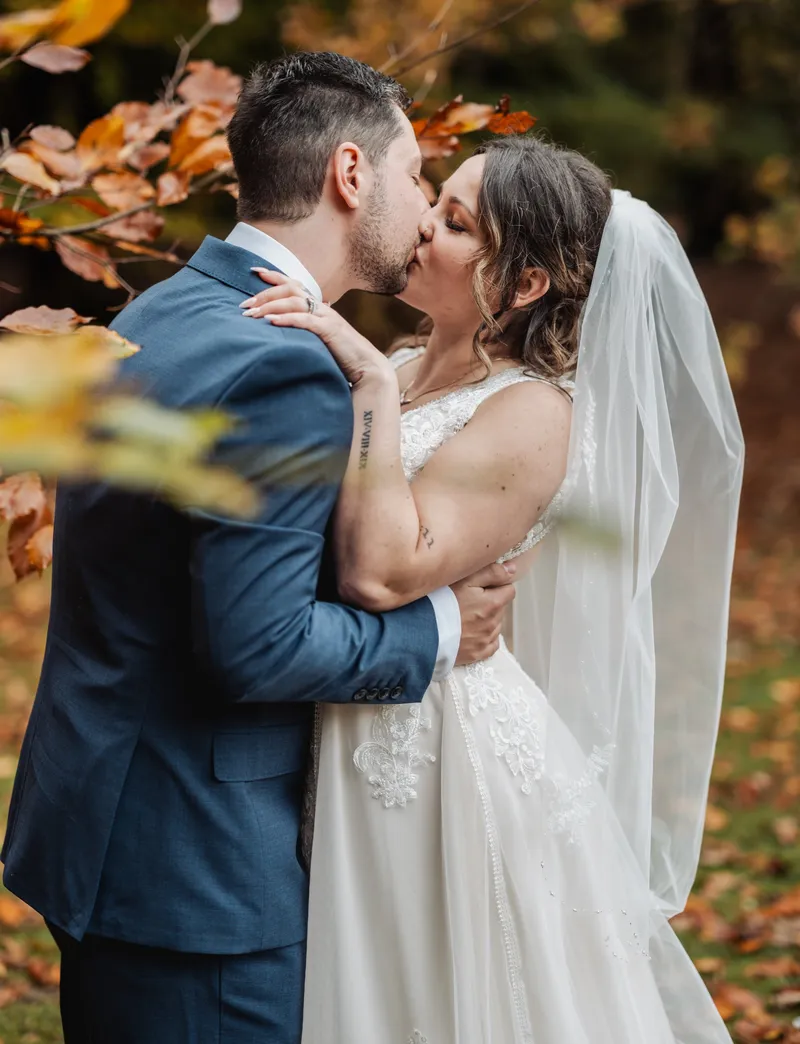Couple kissing under golden autumn leaves at Oakwood House