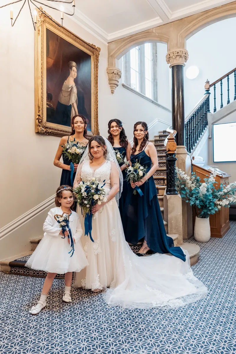 Bride, bridesmaids and flower girl on the grand staircase at Oakwood House