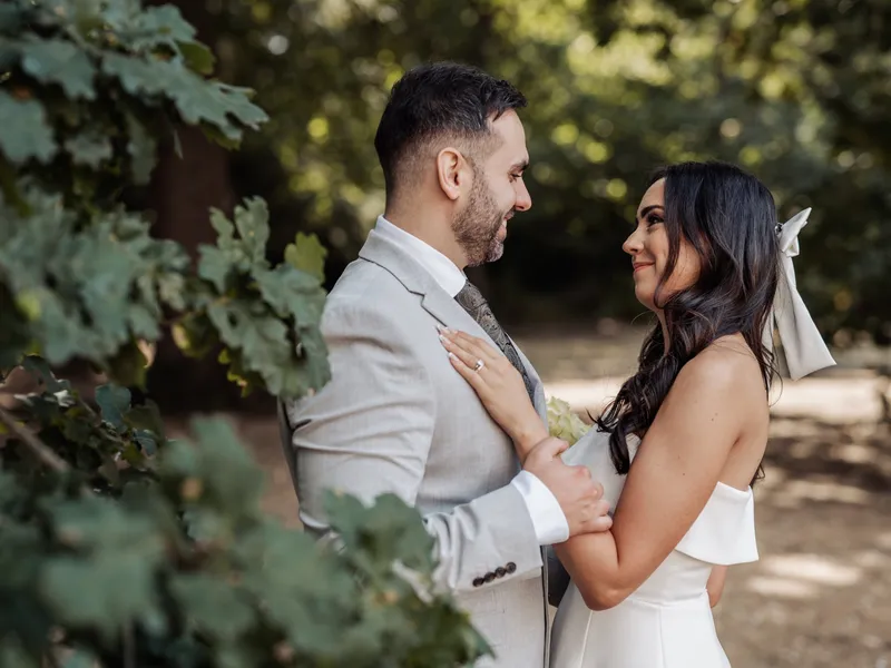 Couple smiling at each other under oak leaves at Oakwood House