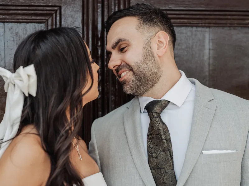 Groom grinning at the bride in front of an old wooden door at Oakwood House
