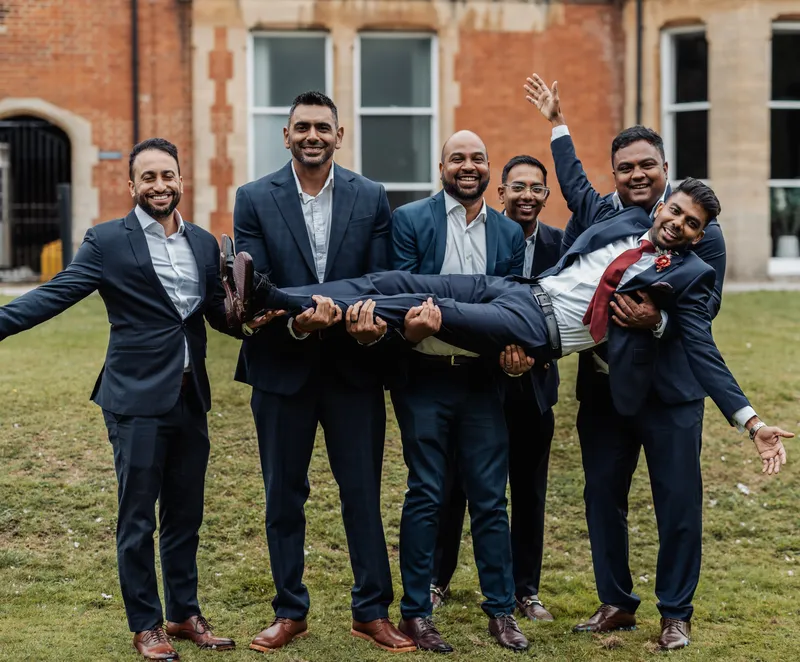 Groomsmen lifting the groom on the lawn at Oakwood House