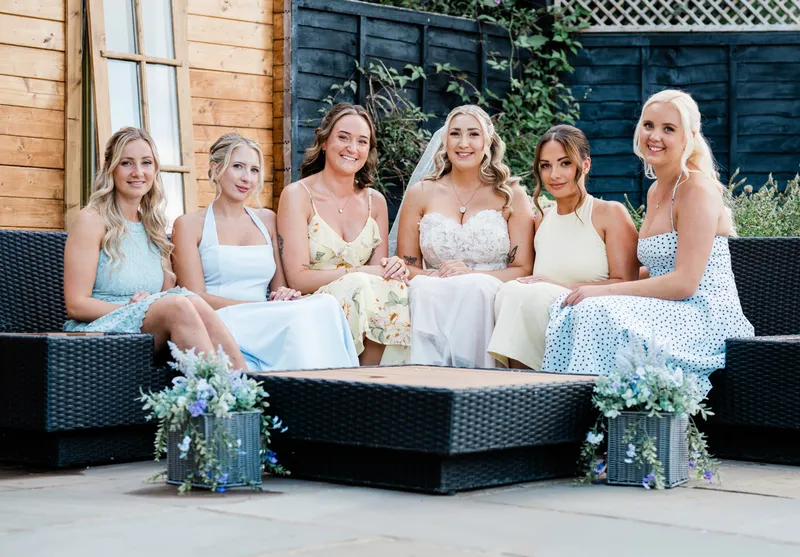 Bride and bridesmaids on the terrace by Oak Lodge at The Orchard