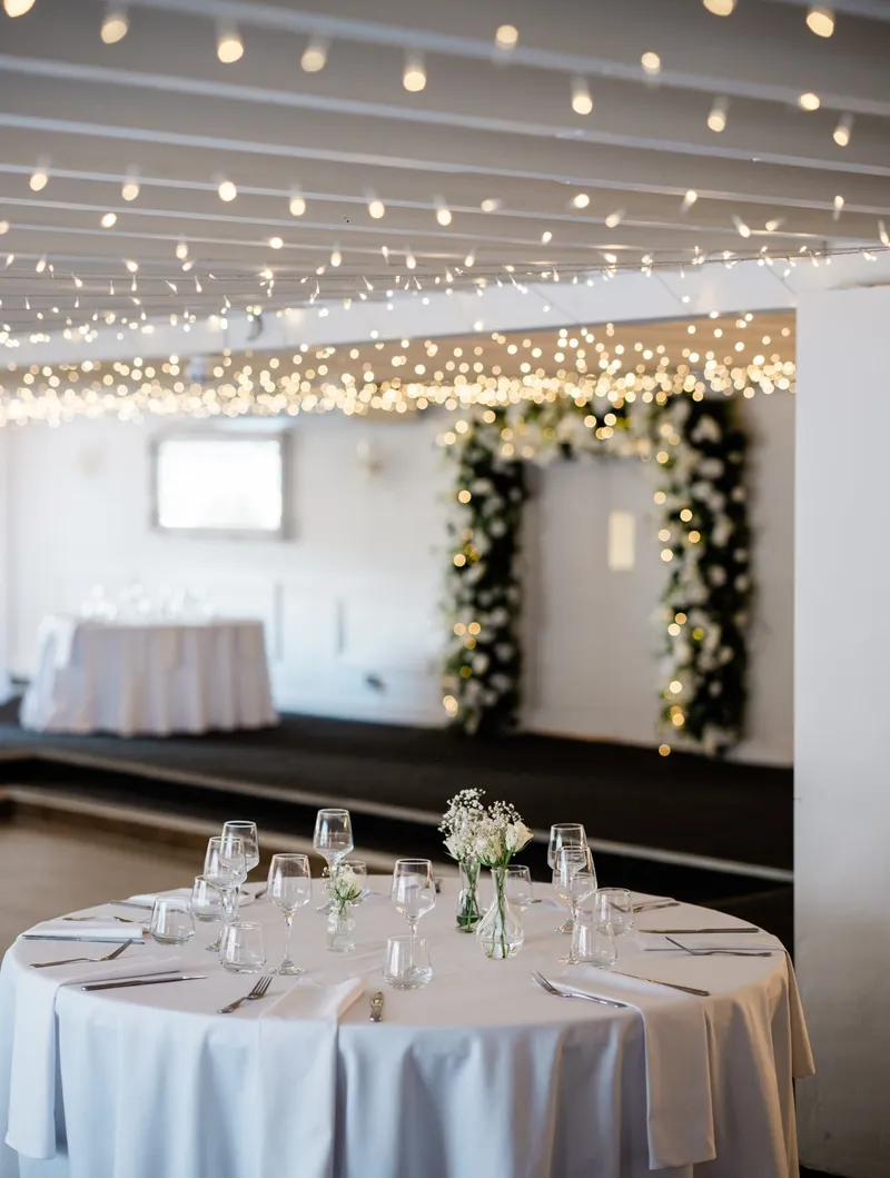 Reception room with fairy lights and a flower arch at The Orchard