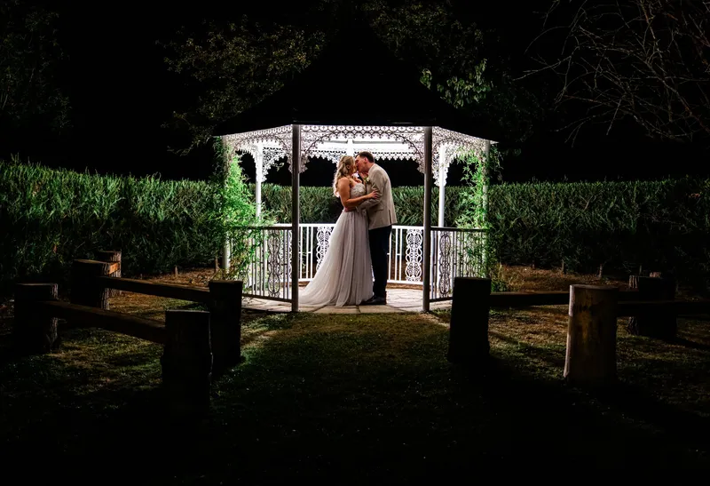 Couple kissing in the lit-up Garden Gazebo at night at The Orchard, Bearsted
