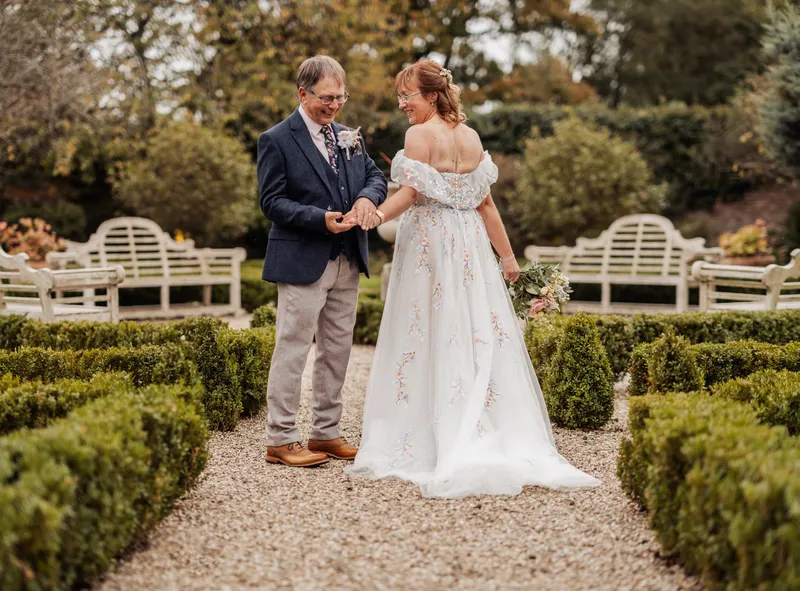 Couple admiring their wedding rings in the box-hedge garden at The Secret Garden, Mersham-le-Hatch